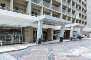 Un hôtel à plusieurs étages doté d’une entrée couverte, de grandes fenêtres et d’un rez-de-chaussée carrelé.