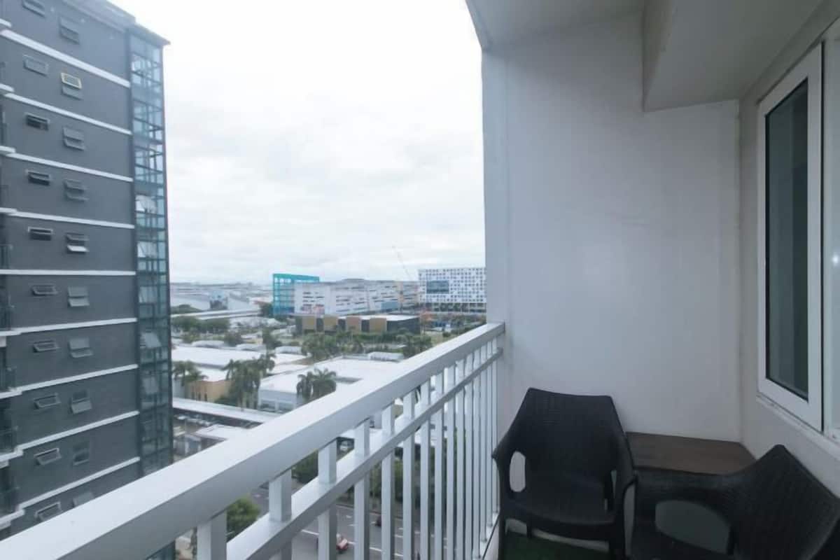 A balcony with a view of a cityscape, including a tall building and a blue structure.