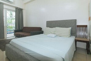 Une chambre d’hôtel avec un grand lit, un canapé, un fauteuil et une vue sur l’extérieur.