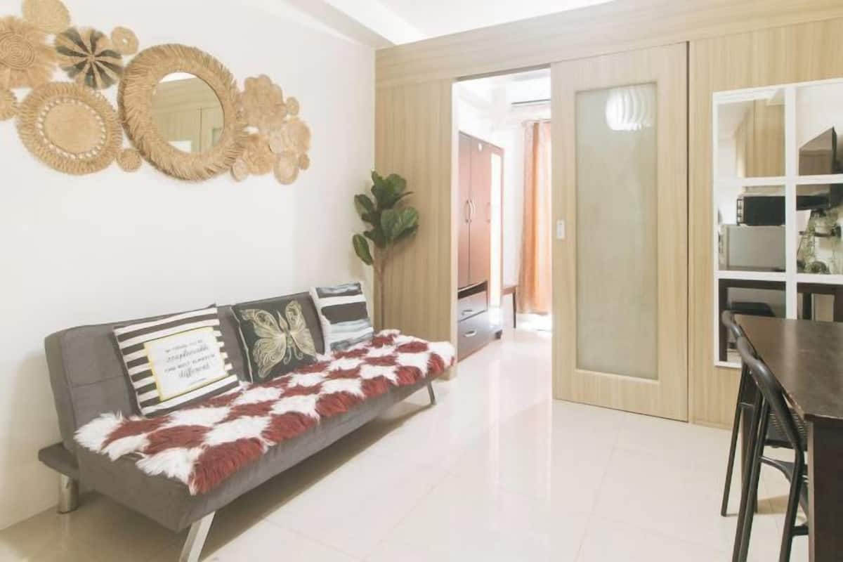 A modern living room with a sofa, decorative mirrors, and a dining area.