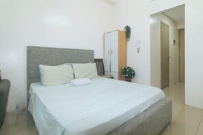 A bedroom with a bed, a wardrobe, a nightstand, and a potted plant. - Lascianos SMDC Shore Residences by RedDoorz (Pasay)