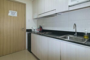 A kitchen with a stainless steel sink, cabinets, and a 'CLEAN AS YOU GO' sign. - Lascianos SMDC Shore Residences by RedDoorz (Pasay)