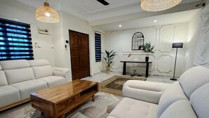 Ein modernes Wohnzimmer mit einer Sofagarnitur, einem Holztisch und einem Essbereich mit Tisch und Stühlen.