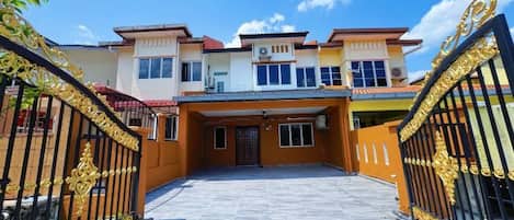 A gated entrance to a multi-story residential building with a central entrance and a driveway leading to the main entrance.