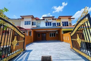 A gated entrance to a multi-story residential building with a central entrance and a driveway leading to the main entrance. - Wawasan Puchong Family-Friendly Spacious Home (Puchong)