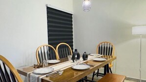 Ein Essbereich mit einem langen Holztisch, gedeckt für vier Personen, umgeben von Holzstühlen mit schwarz-weißen Streifen an der Rückenlehne.