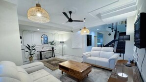 Ein modernes Wohnzimmer mit einem weißen Sofa, einem Holztisch und einem Deckenventilator.