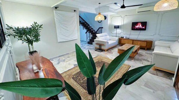 Ein modernes Wohnzimmer mit Treppe, weißen Sofas, einem Holztisch und einem an der Wand montierten Fernseher.