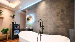 A modern bathroom with a freestanding bathtub, a small bench, and a digital information kiosk. - Elegant Feel Inn - M&A (Ho Chi Minh City)
