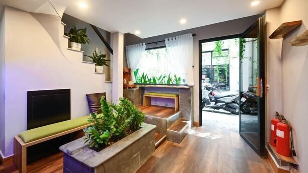 A modern interior with a bench, plants, a staircase, and a motorcycle visible through an open door. - Elegant Feel Inn - M&A (Ho Chi Minh City)
