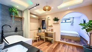 A modern bathroom with a bathtub, sink, and shower. There is a desk with a chair and a bed with a window. - Elegant Feel Inn - M&A (Ho Chi Minh City)