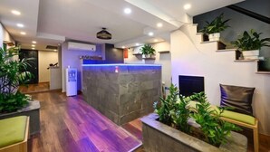 A modern reception area with a stone counter, seating, and potted plants. - Elegant Feel Inn - M&A (Ho Chi Minh City)