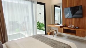 A modern hotel room with a large bed, a TV mounted on the wall, a small wooden table, and a view of the outdoors. - The Eight Bali Seminyak (Bali)