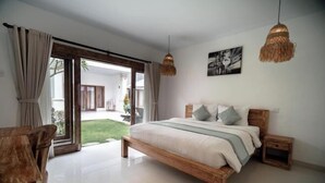 A bedroom with a large bed, wooden headboard, and a view of a garden through a sliding door. - The Eight Bali Seminyak (Bali)