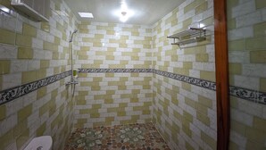 A small, tiled bathroom with a shower, a toilet, and a towel rack. - Nusa Pelangi Bungalow (Penida Island)