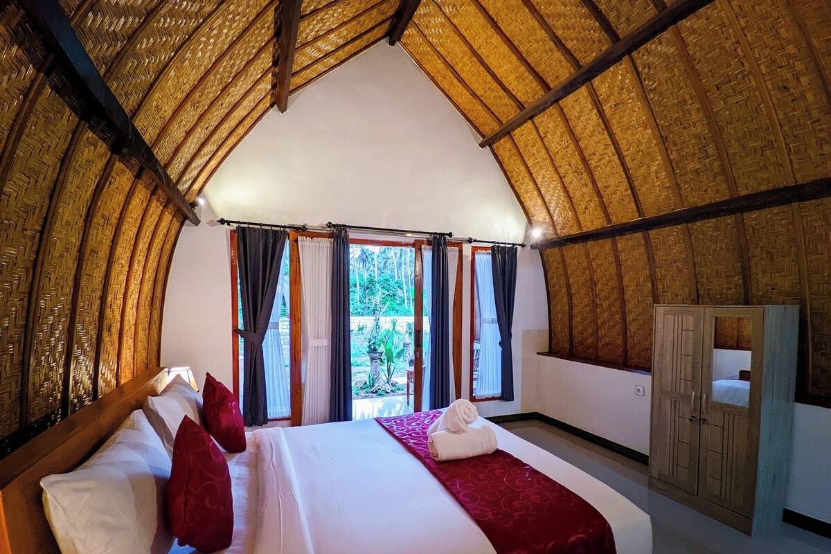 Een kamer met een bed, gordijnen en een kledingkast.