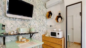 A kitchen with a flat-screen TV, a microwave, a wooden cabinet, and a glass table. - 'Jungle' Guest Room with Shared Pool, Wi-Fi, and Air Conditioning (Saint-Raphaël)