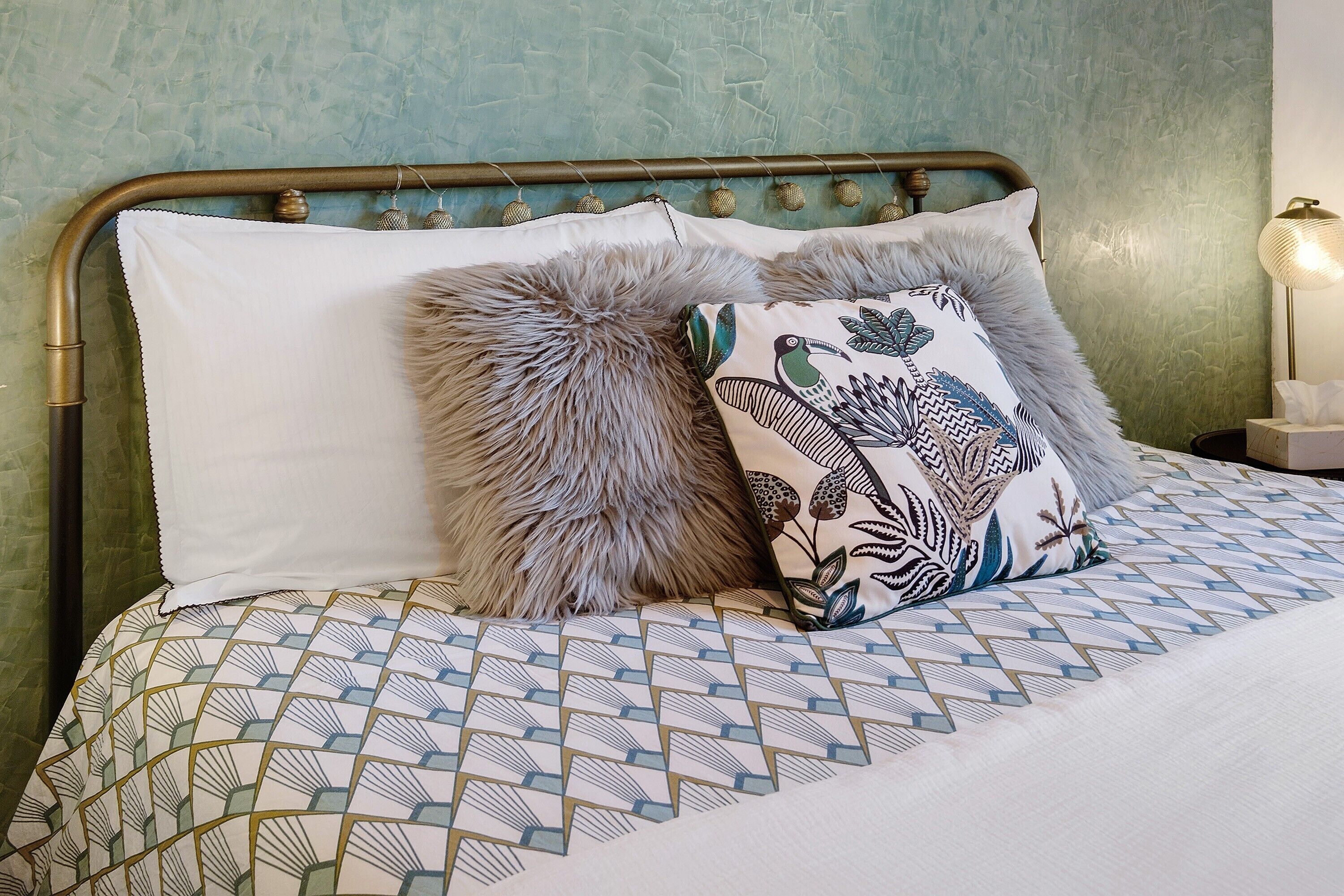 Un lit avec une literie à motifs, un coussin décoratif et une tête de lit.