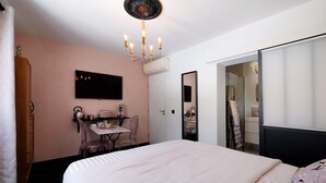 A bedroom with a bed, a desk, a chair, a TV, and a mirror. - Pink Suite Guest Room with Shared Pool, Wi-Fi, and Air Conditioning (Saint-Raphaël)