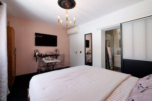 Una camera da letto con un letto, una scrivania, una sedia, un televisore e uno specchio.