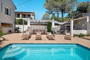En swimmingpool med solstolar, en pergola och en uteplats.