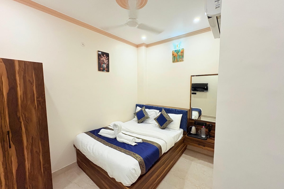 A neatly made bed with blue and white bedding, a wooden headboard, and a small bedside table with a lamp.