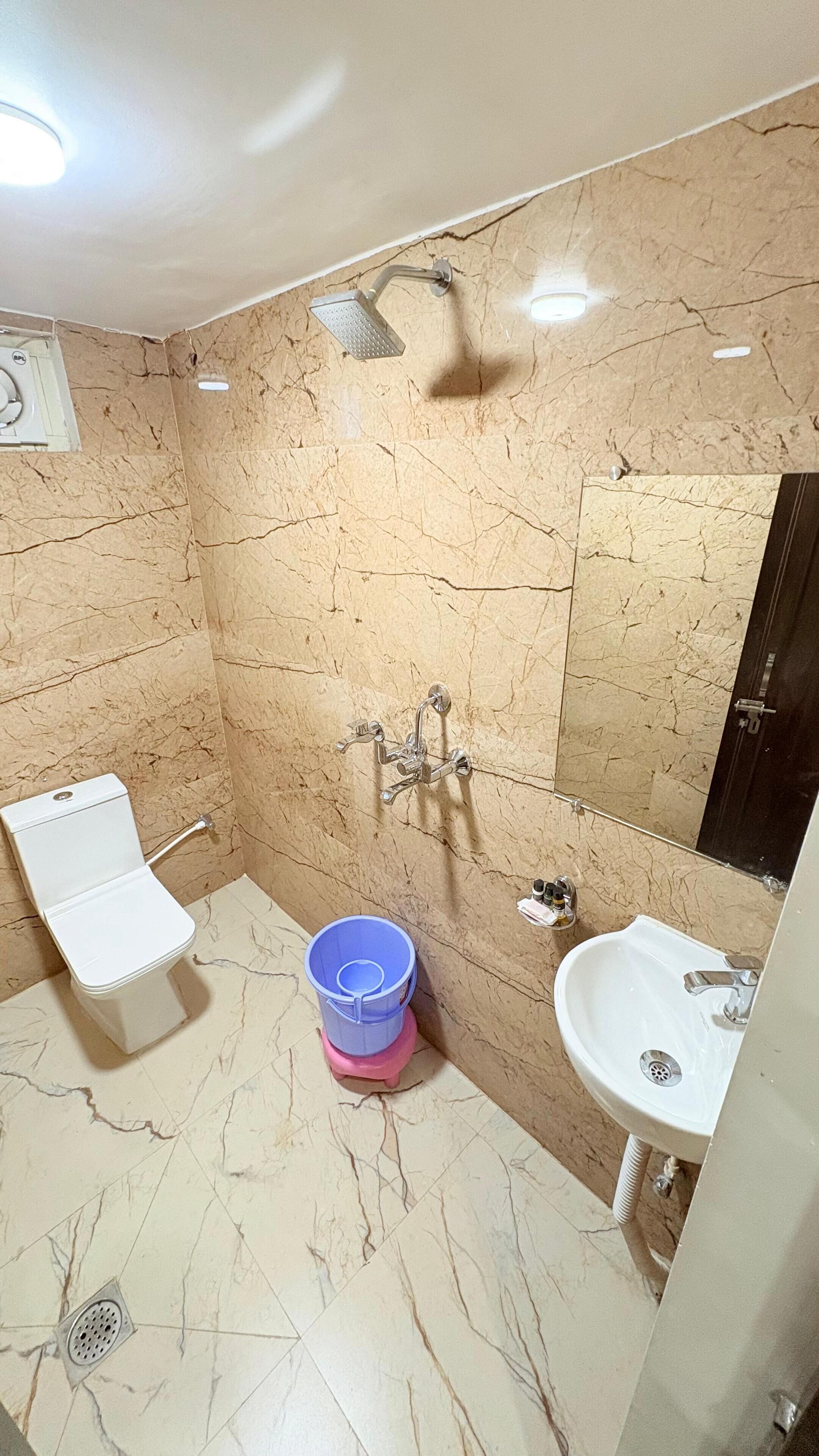Een badkamer met een wit wastafelmeubel, een spiegel, een douche en een toilet.