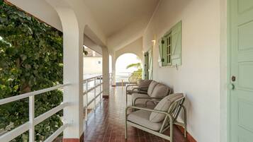 A corridor with a white railing, green shutters, and a sofa.