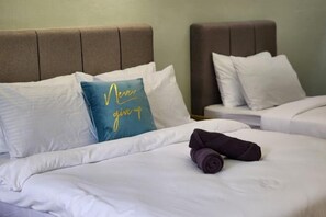 Hotellihuone, jossa on kaksi sänkyä. Jokaisessa sängyssä on pääty, valkoiset vuodevaatteet ja tekstillä varustettu tyyny.