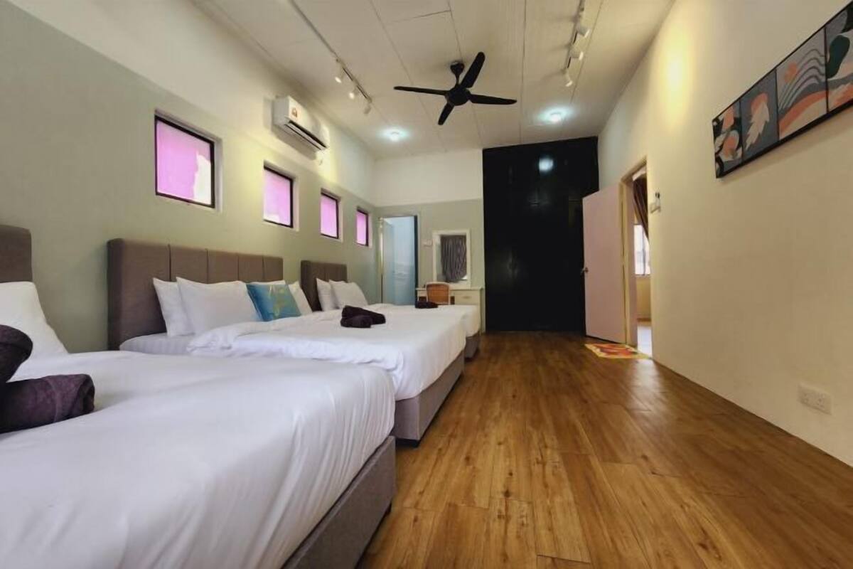 Une chambre d’hôtel avec deux lits, un plancher en bois, un ventilateur de plafond et des œuvres d’art accrochées aux murs.