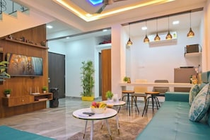Un salon moderne avec un canapé, une table basse et un téléviseur. Il y a également un coin repas avec des chaises et une table.