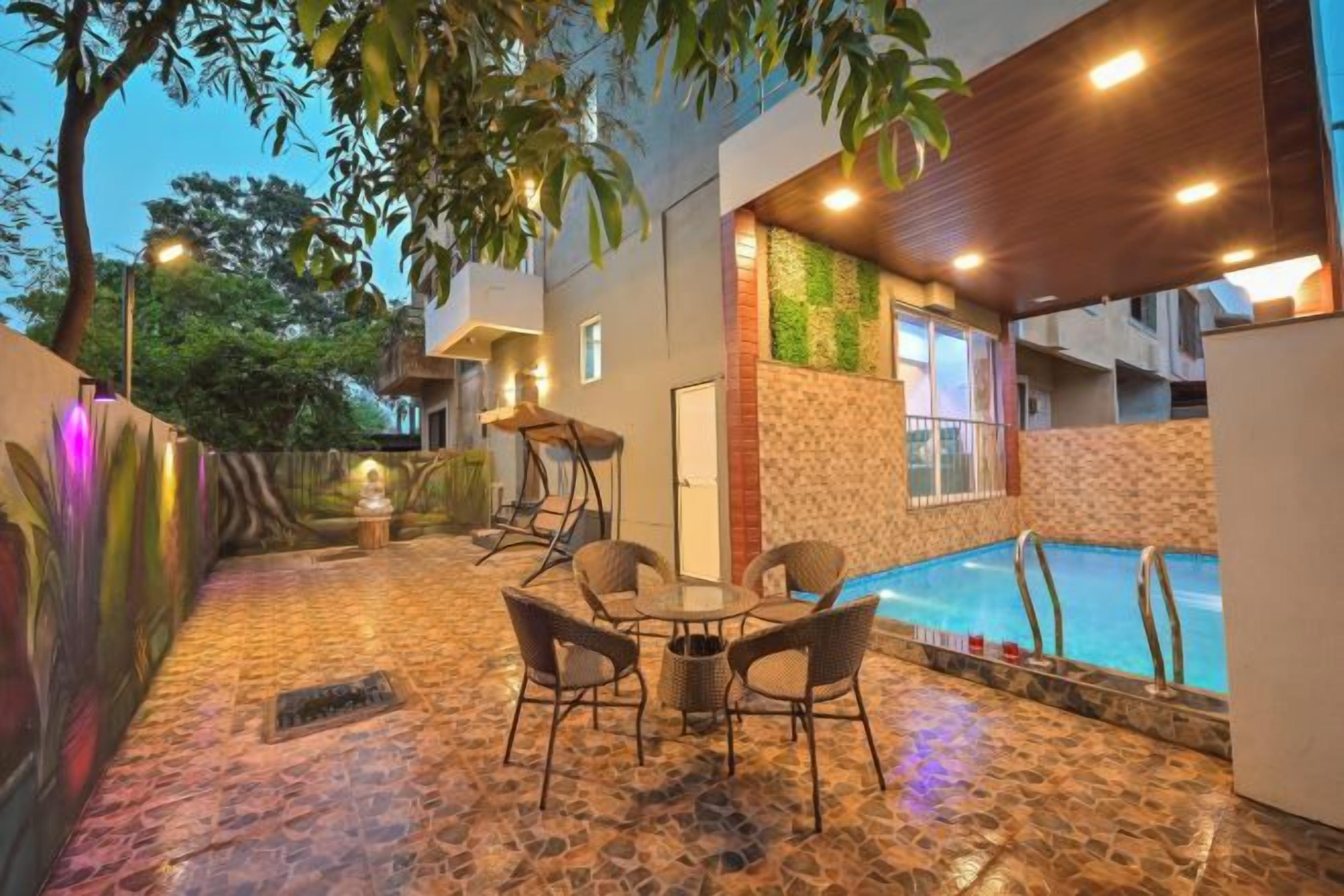 An outdoor pool area with a stone floor, surrounded by a wooden deck and a glass enclosure.