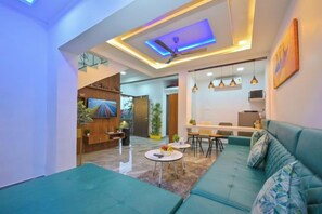 A modern living room with a sofa, coffee table, and a ceiling fan. - HashTag Villa 2BHK in Lonavala (Kune N.m.)