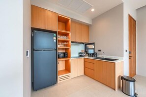 A compact kitchen with a refrigerator, oven, and sink. - Long One A5 (Phuket)