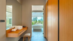 A modern bathroom with a built-in bench, a large bathtub, and a view of the outdoors. - Long One A5 (Phuket)