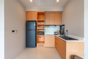 A compact kitchen with a refrigerator, microwave, and sink. - Long One A5 (Phuket)