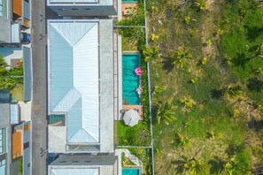 An aerial view of a hotel with a rooftop pool, a covered outdoor area, and surrounding greenery. - Long One A5 (Phuket)