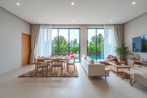 A spacious living room with a dining area, large windows, a pool, and a TV mounted on the wall. - Long One A5 (Phuket)