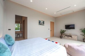 A modern bedroom with a bed, a television, a desk, and a window. - Long One A5 (Phuket)