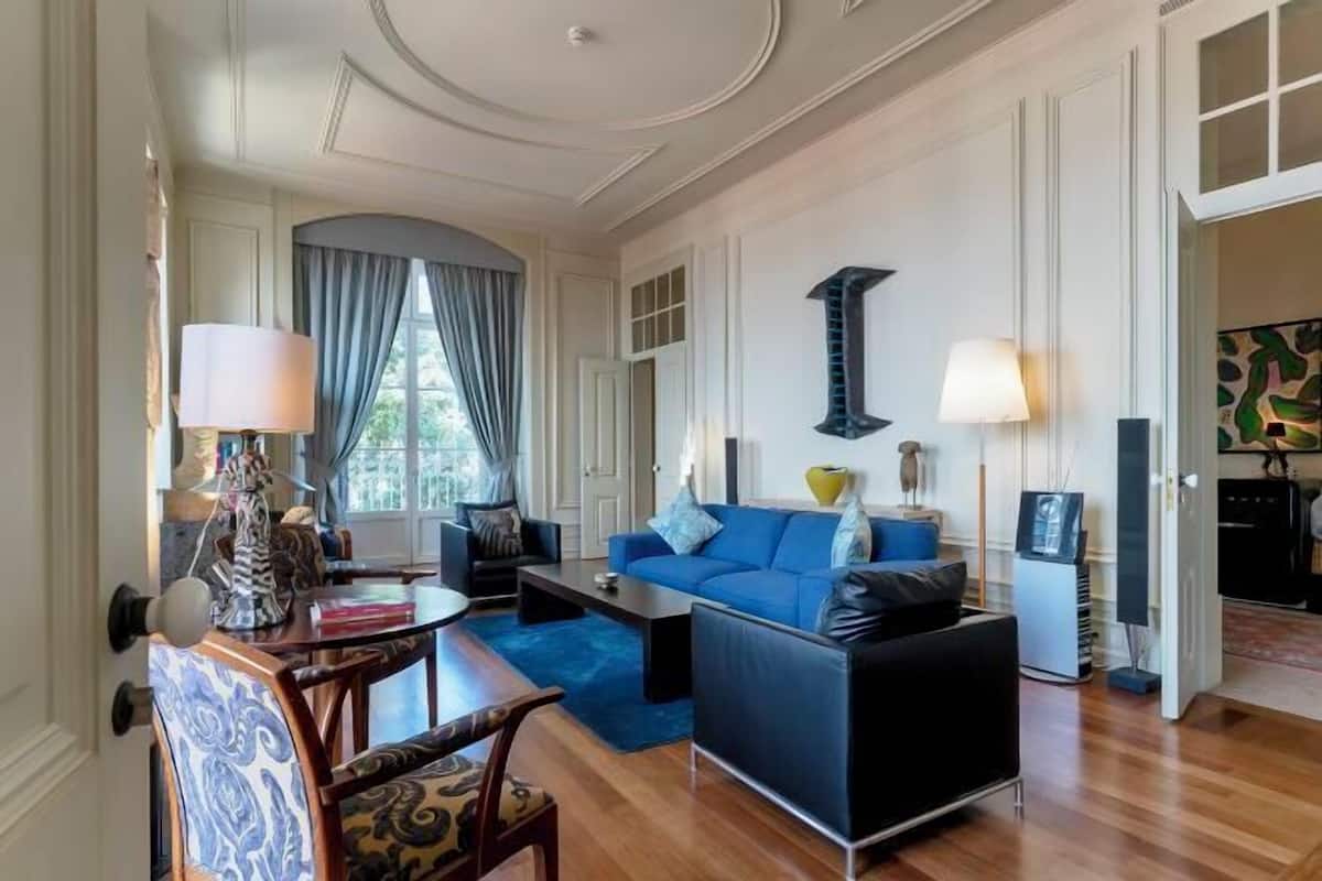 Una sala de estar moderna con un sofá azul, una mesa de centro y un comedor con sillas y una mesa.