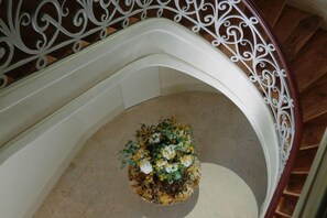 A staircase with a white railing and a floral arrangement at the bottom. - Verride Palácio Santa Catarina (Lisbon)
