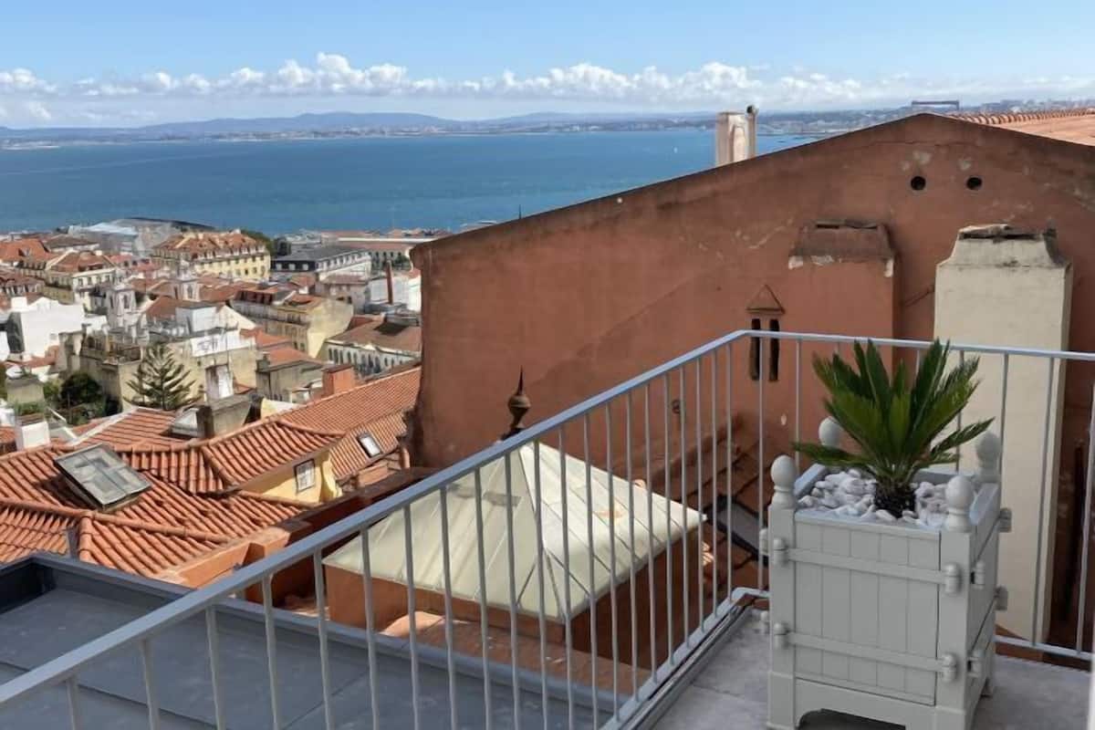 Una terraza en la azotea con vistas al mar y al paisaje urbano.