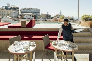 A rooftop terrace with seating and tables, overlooking a cityscape. - Verride Palácio Santa Catarina (Lisbon)