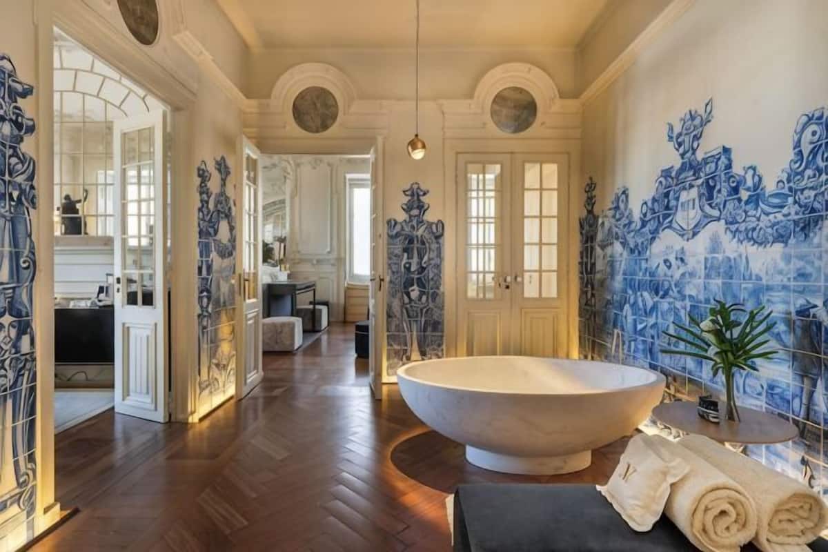 Un baño amplio con una bañera independiente grande, un lavamanos y un espejo.