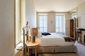 Una habitación de hotel con cama, mesita de noche, lámpara, ventana y vistas al exterior.