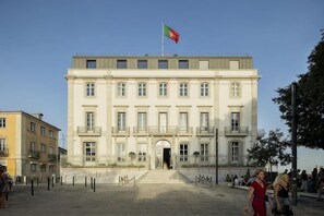 A large, multi-story building with a central entrance and a flag on top. - Verride Palácio Santa Catarina (Lisbon)