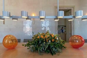 A reception area with a wooden reception desk, a floral centerpiece, and a modern light fixture. - Verride Palácio Santa Catarina (Lisbon)