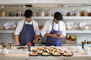 Two chefs in a kitchen with various food items and cooking utensils on the counter. - Verride Palácio Santa Catarina (Lisbon)