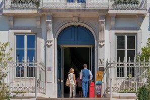 A building entrance with a large arched doorway, a metal fence, and a signboard. - Verride Palácio Santa Catarina (Lisbon)