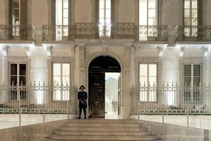 Un'imponente ingresso caratterizzato da una doppia scala, un'ampia porta ad arco e una guardia in servizio all'estremità.